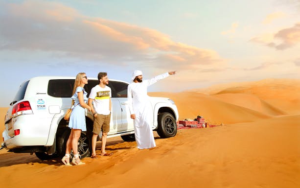 Traveller with guide beside SUV after dune bashing in desert safari.