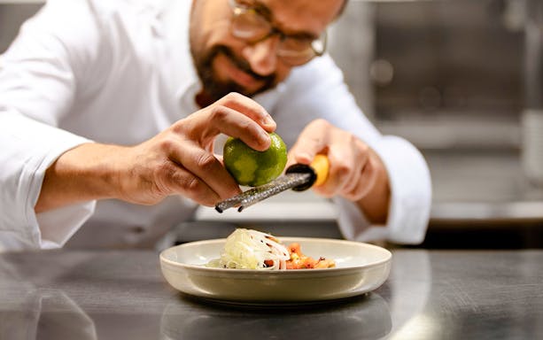 Chef zesting lime over dish on Bateaux Parisiens cruise in Paris, France.