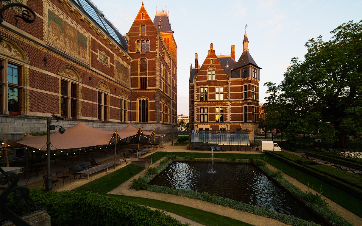 Rijksmuseum garden with pond and historic brick architecture in Amsterdam.