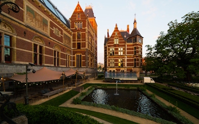 Rijksmuseum garden with pond and historic brick architecture in Amsterdam.