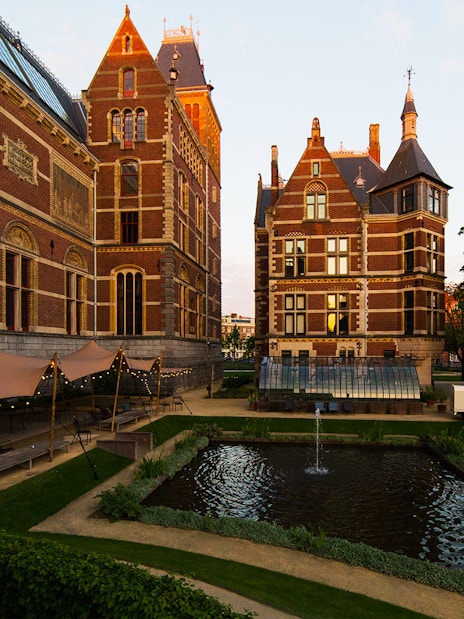 Rijksmuseum garden with pond and historic brick architecture in Amsterdam.