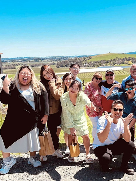 Group enjoying Yarra Valley wine tour with vineyard view.