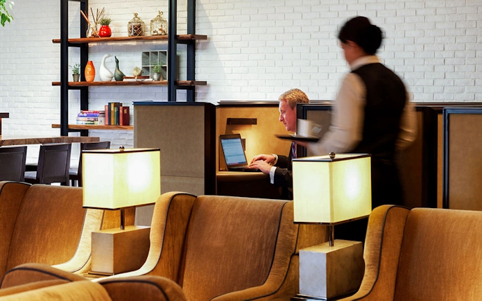 Heathrow Plaza Premium Lounge seating area with guest using laptop and staff serving.