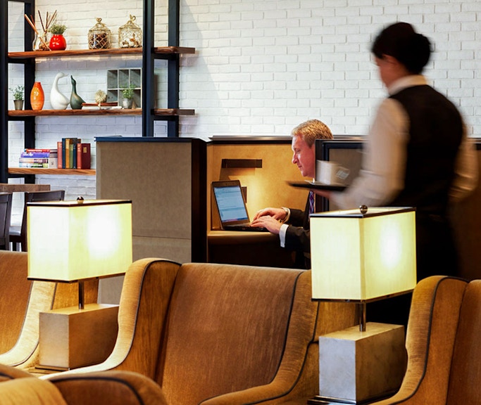 Heathrow Plaza Premium Lounge seating area with guest using laptop and staff serving.