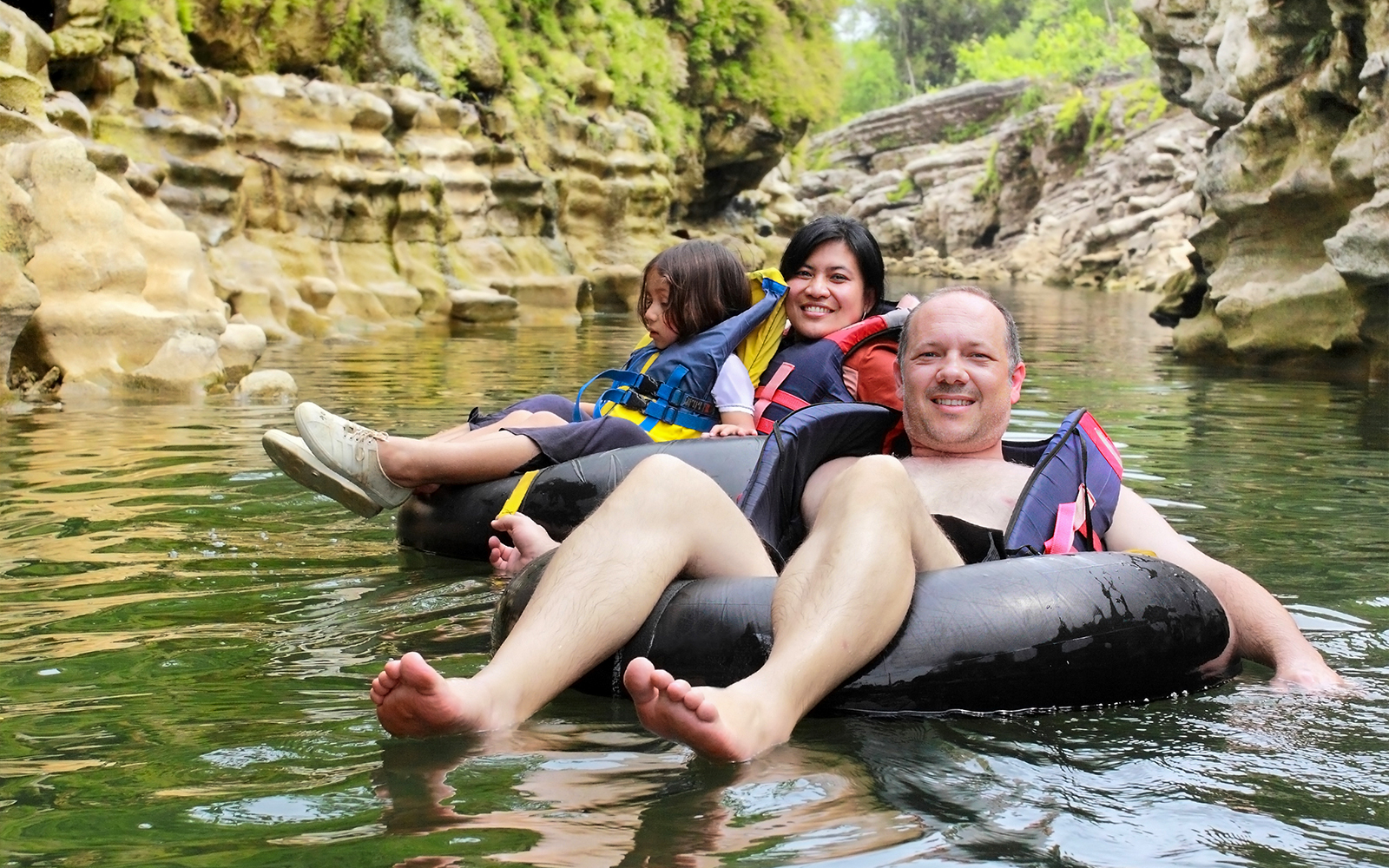 People tubing down Cairns River in Australia amidst lush greenery.