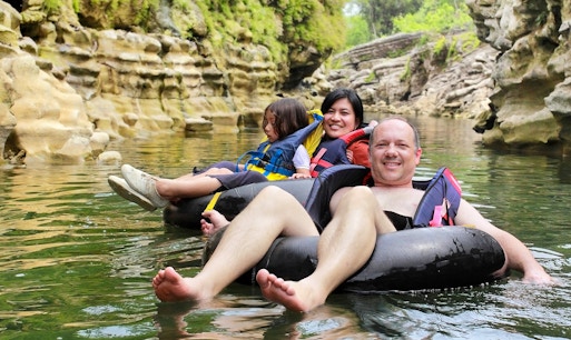 People tubing down Cairns River in Australia amidst lush greenery.