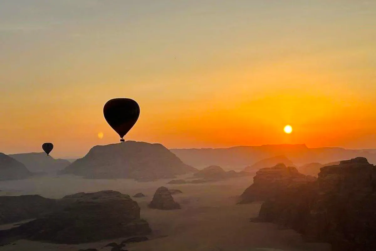 Hot air balloons over Wadi Rum desert at sunrise.