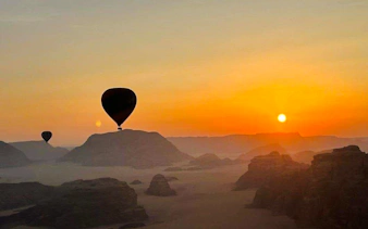 Hot air balloons over Wadi Rum desert at sunrise.