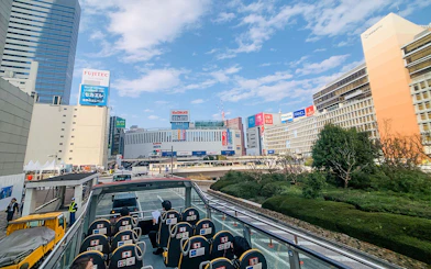 Tourists on Sky Hop Bus in Tokyo viewing cityscape and landmarks.