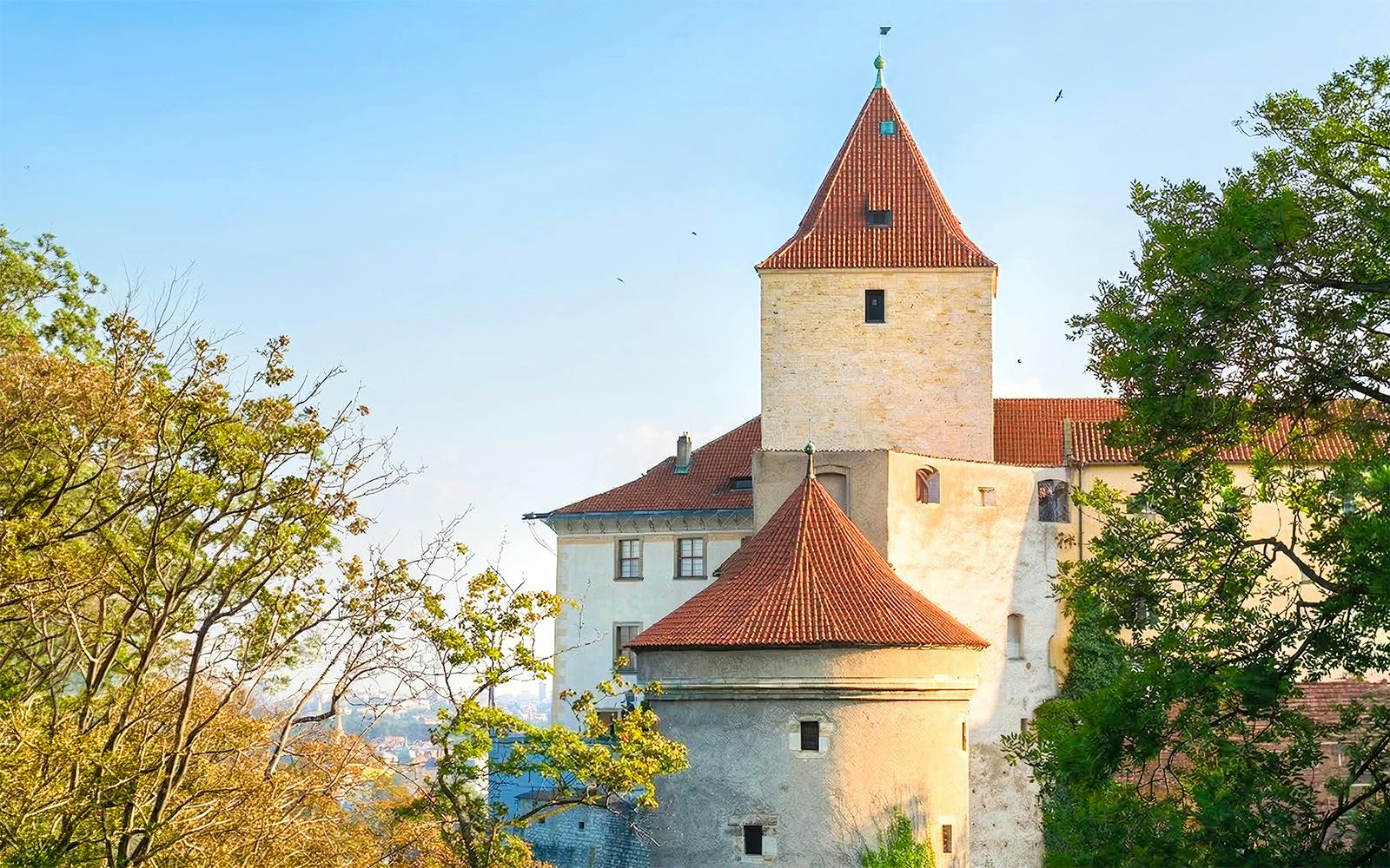 Daliborka Tower and Black Tower at Prague Castle surrounded by trees.