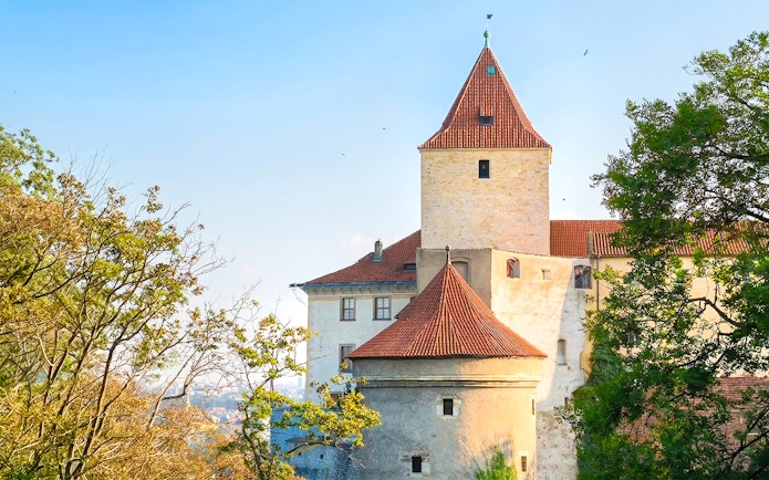 Daliborka Tower and Black Tower at Prague Castle surrounded by trees.