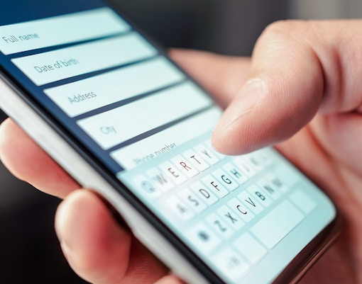 Person entering information on a smartphone form.