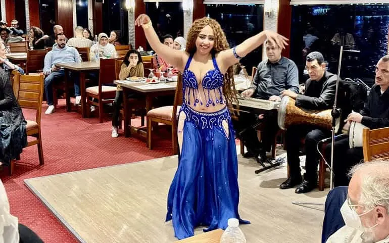 Belly dancer performing on a Cairo Nile dinner cruise with live music and audience.