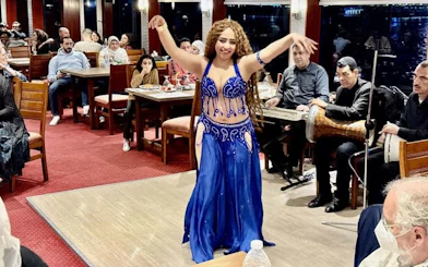 Belly dancer performing on a Cairo Nile dinner cruise with live music and audience.