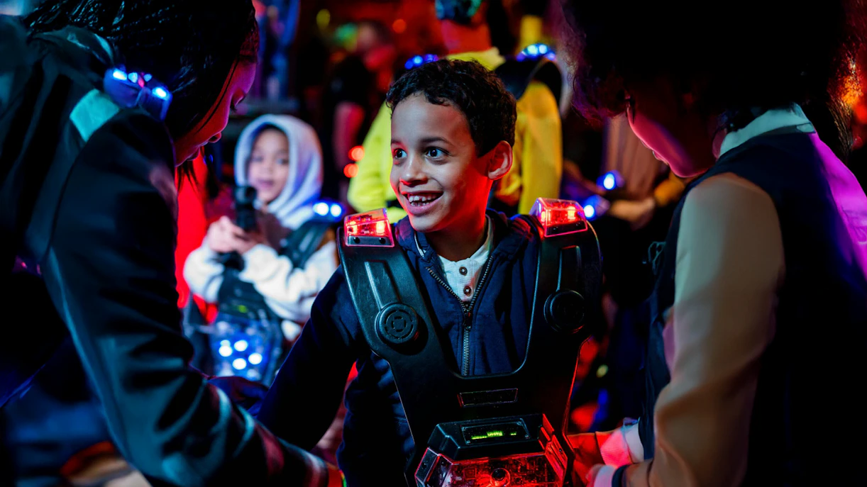 Children playing laser tag in Rotterdam with glowing vests and equipment.
