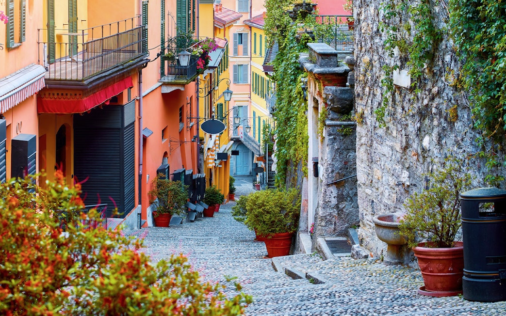 Cobblestone alley with steps and colorful buildings in Como, Italy.