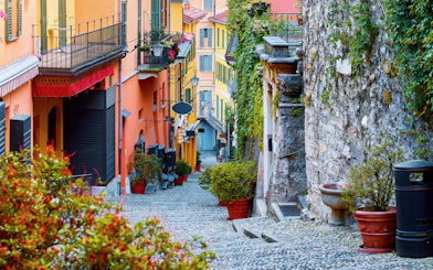 Cobblestone alley with steps and colorful buildings in Como, Italy.