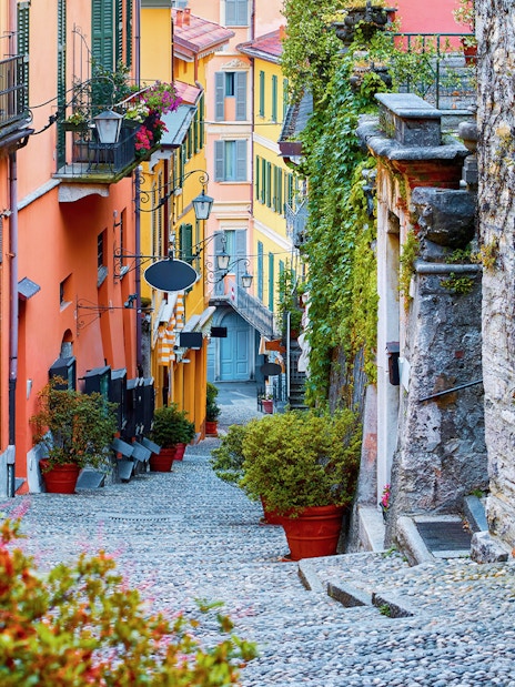 Cobblestone alley with steps and colorful buildings in Como, Italy.