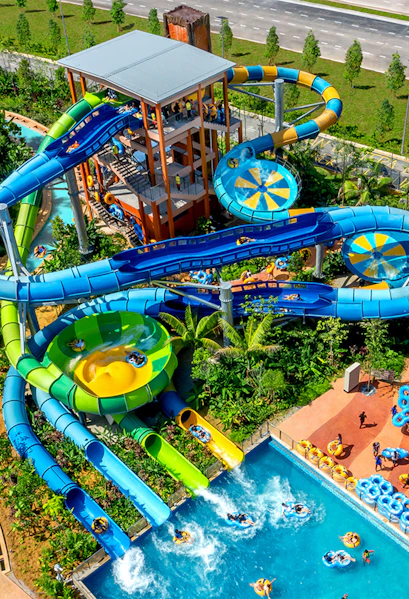 Water slides and pools at SplashMania water park with people enjoying rides.