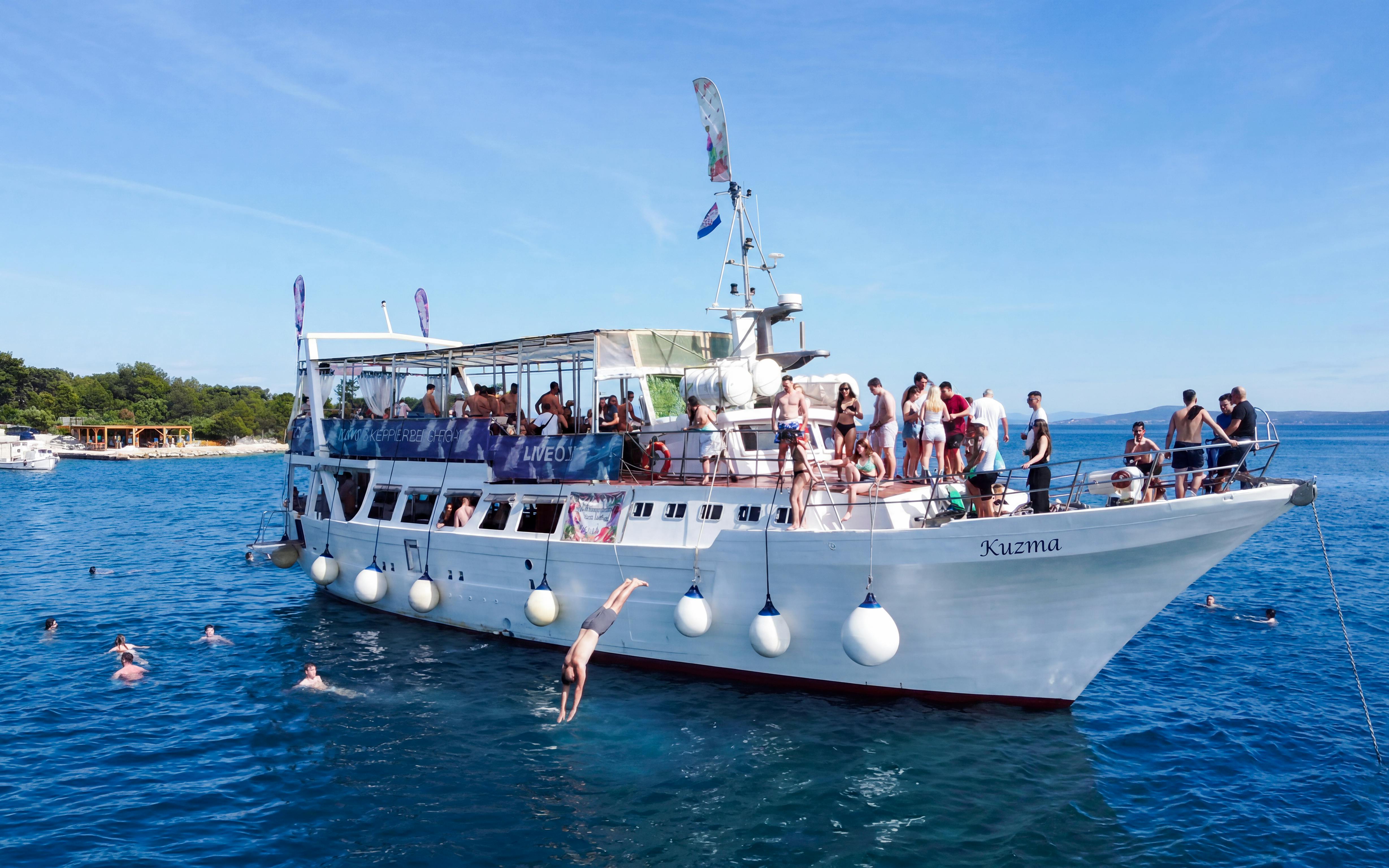 Tourists diving from a boat near an underwater museum and beach resort.