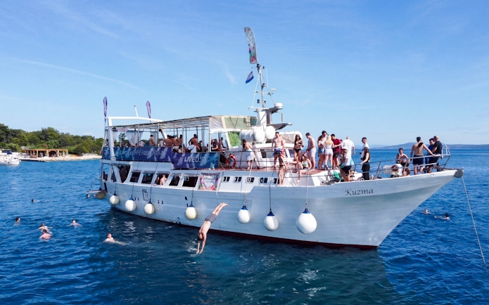 Tourists diving from a boat near an underwater museum and beach resort.