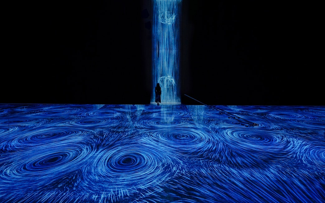 teamLab Planets Tokyo, blue light vortices installation with person standing in the flow.