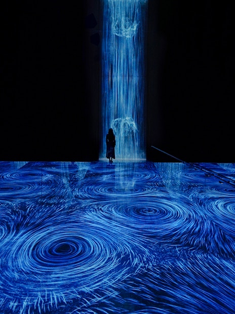 teamLab Planets Tokyo, blue light vortices installation with person standing in the flow.