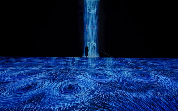 teamLab Planets Tokyo, blue light vortices installation with person standing in the flow.