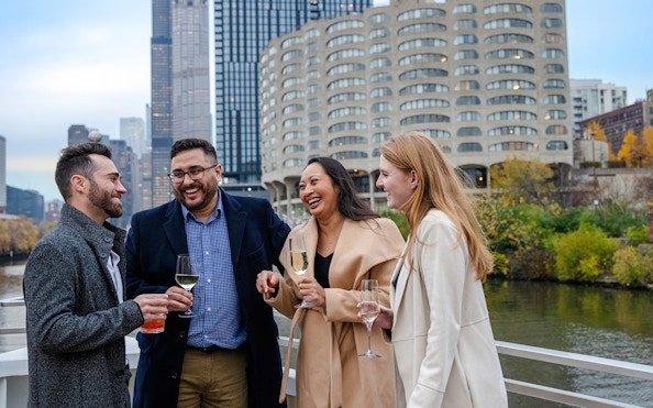 Guests enjoying drinks on a Lake Michigan dinner cruise with Chicago skyline in the background.