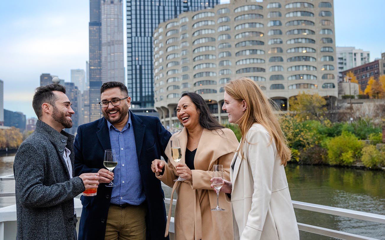 Guests enjoying drinks on a Lake Michigan dinner cruise with Chicago skyline in the background.