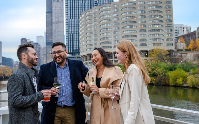 Guests enjoying drinks on a Lake Michigan dinner cruise with Chicago skyline in the background.