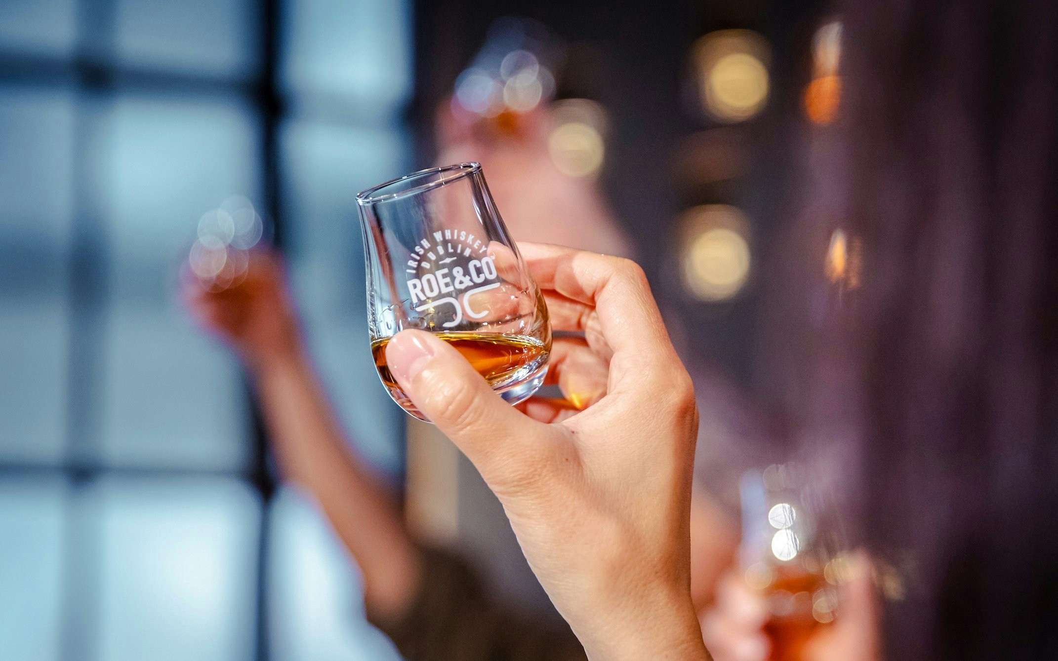 Hand holding a whiskey glass at Roe & Co Distillery tasting session.