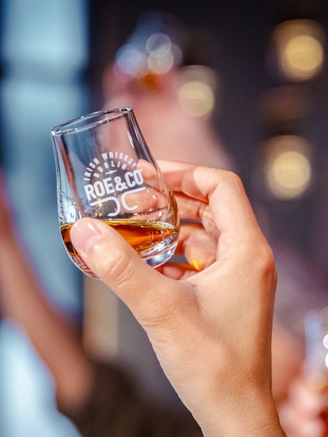 Hand holding a whiskey glass at Roe & Co Distillery tasting session.