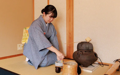 Tea ceremony participant preparing matcha in traditional Japanese room.