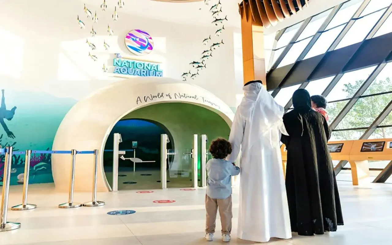 Family entering National Aquarium Abu Dhabi through main entrance.