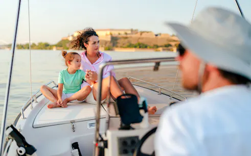 Mother and daughter sitting on a speedboat with a scenic view in the background.
