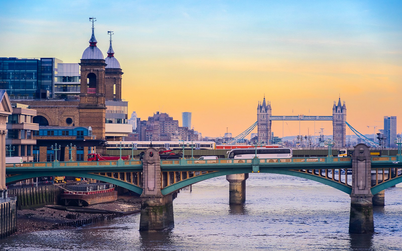 Southwark Bridge over the Thames with Tower Bridge in the background at sunset, London.