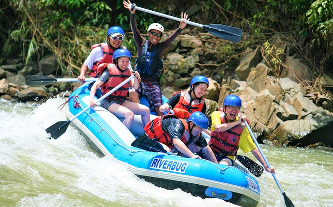 Group rafting on Kampar River, Malaysia, navigating rapids with paddles.