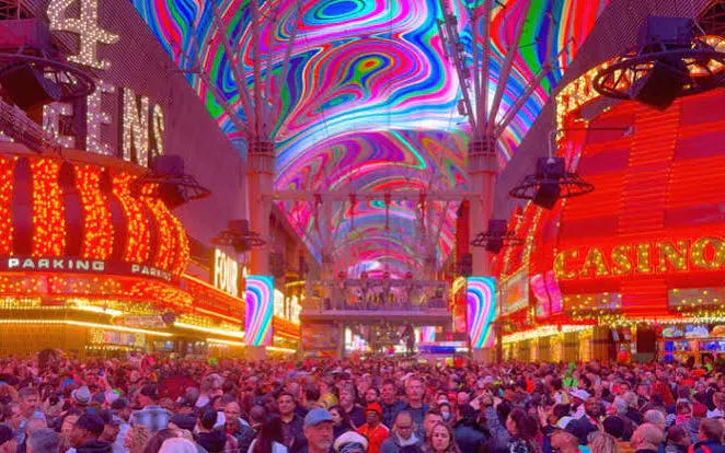 Crowd under vibrant lights at Fremont Street, Downtown Las Vegas bar crawl.