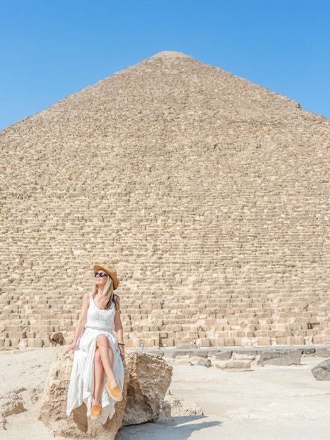 Tourist sitting on rock in front of Giza Pyramid, Egypt.