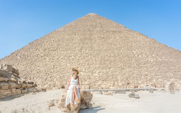 Tourist sitting on rock in front of Giza Pyramid, Egypt.