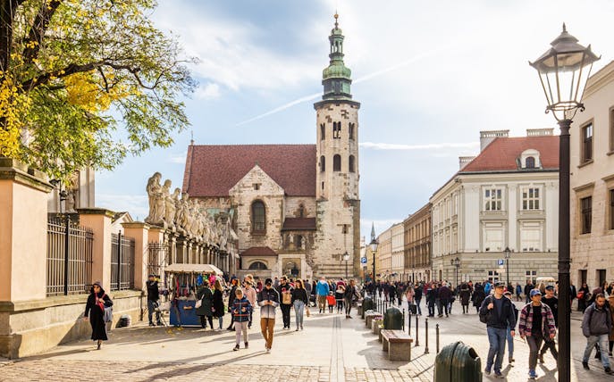 Krakow street scene with St. Andrew's Church, people walking, and market stalls.
