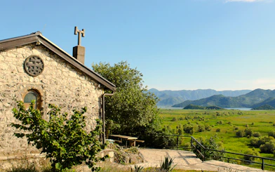 Kom Monastery stone building with Lake Skadar and mountains in the background.