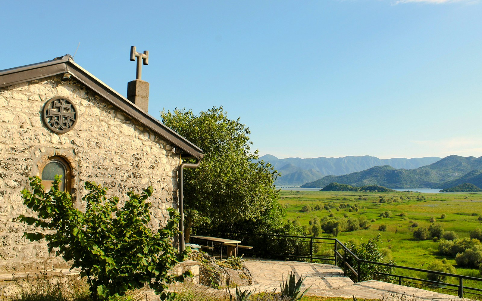 Kom Monastery stone building with Lake Skadar and mountains in the background.