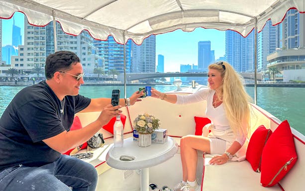 Couple enjoying a boat ride with drinks on a Duffy by Love Boats tour in Dubai Marina.