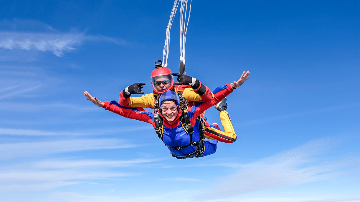 Tandem skydivers freefalling over Abu Dhabi with clear blue skies.