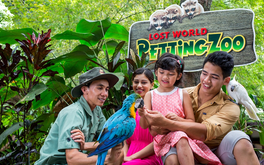 Family interacting with parrots at Lost World Petting Zoo, Sunway Lost World of Tambun, Malaysia.