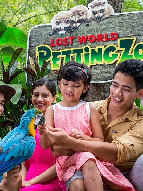 Family interacting with parrots at Lost World Petting Zoo, Sunway Lost World of Tambun, Malaysia.