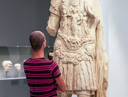 Tourist viewing ancient statue at Heraklion Archaeological Museum, Crete, Greece.