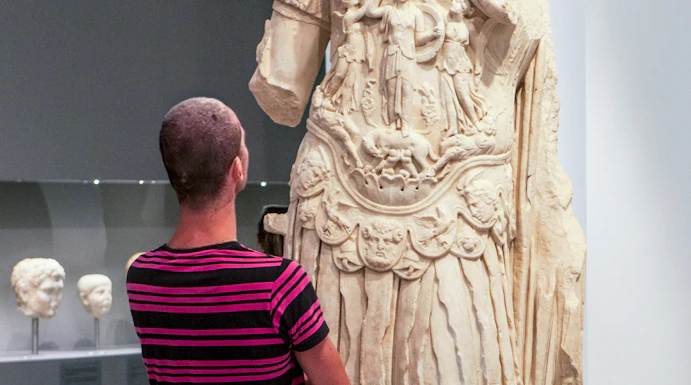 Tourist viewing ancient statue at Heraklion Archaeological Museum, Crete, Greece.